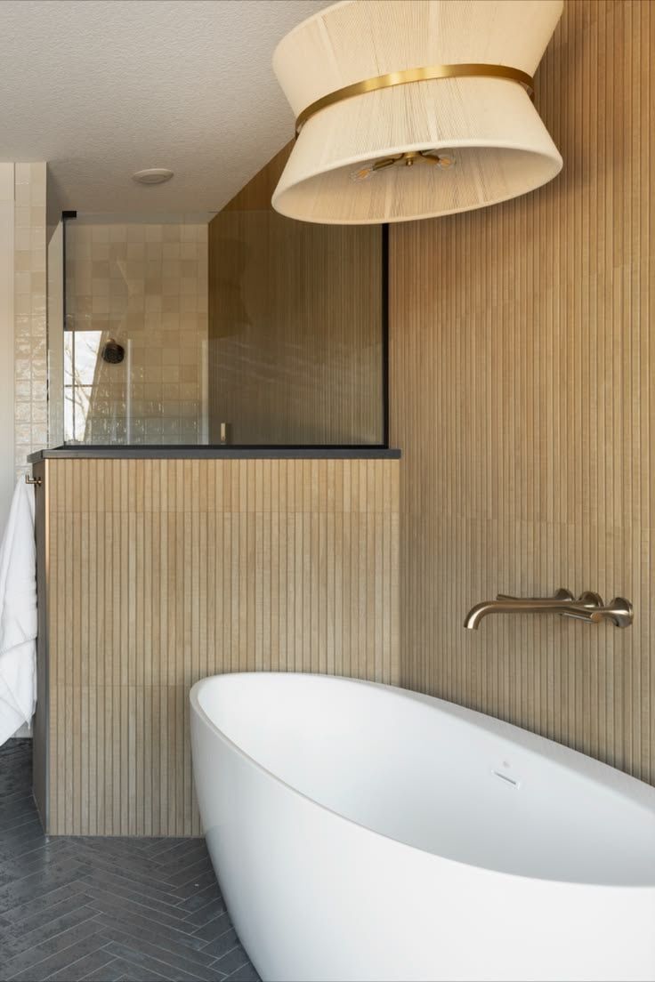 Modern bathroom with fluted tile walls, a freestanding tub and herringbone floor