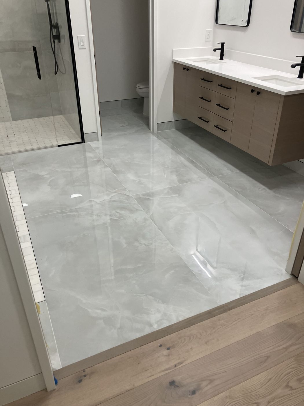Polished large-format marble-look floor tile in a master bathroom