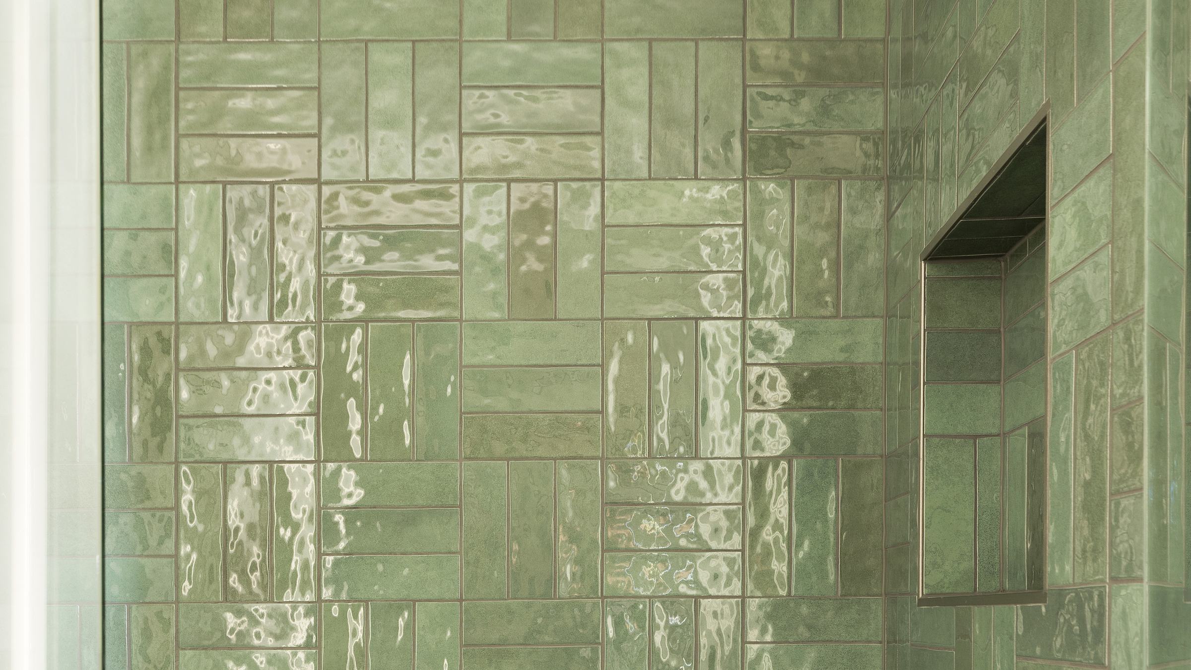 Shower with glossy green handmade-look tile and a recessed niche