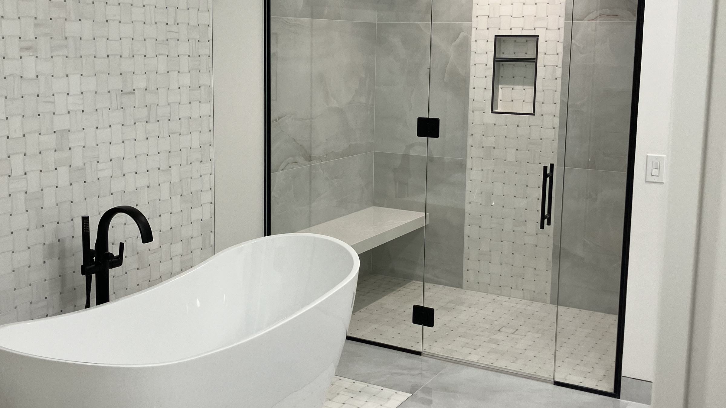 Bathroom by Custom Tile Interiors: freestanding tub on a basketweave mosaic and a glass shower with large-format tile