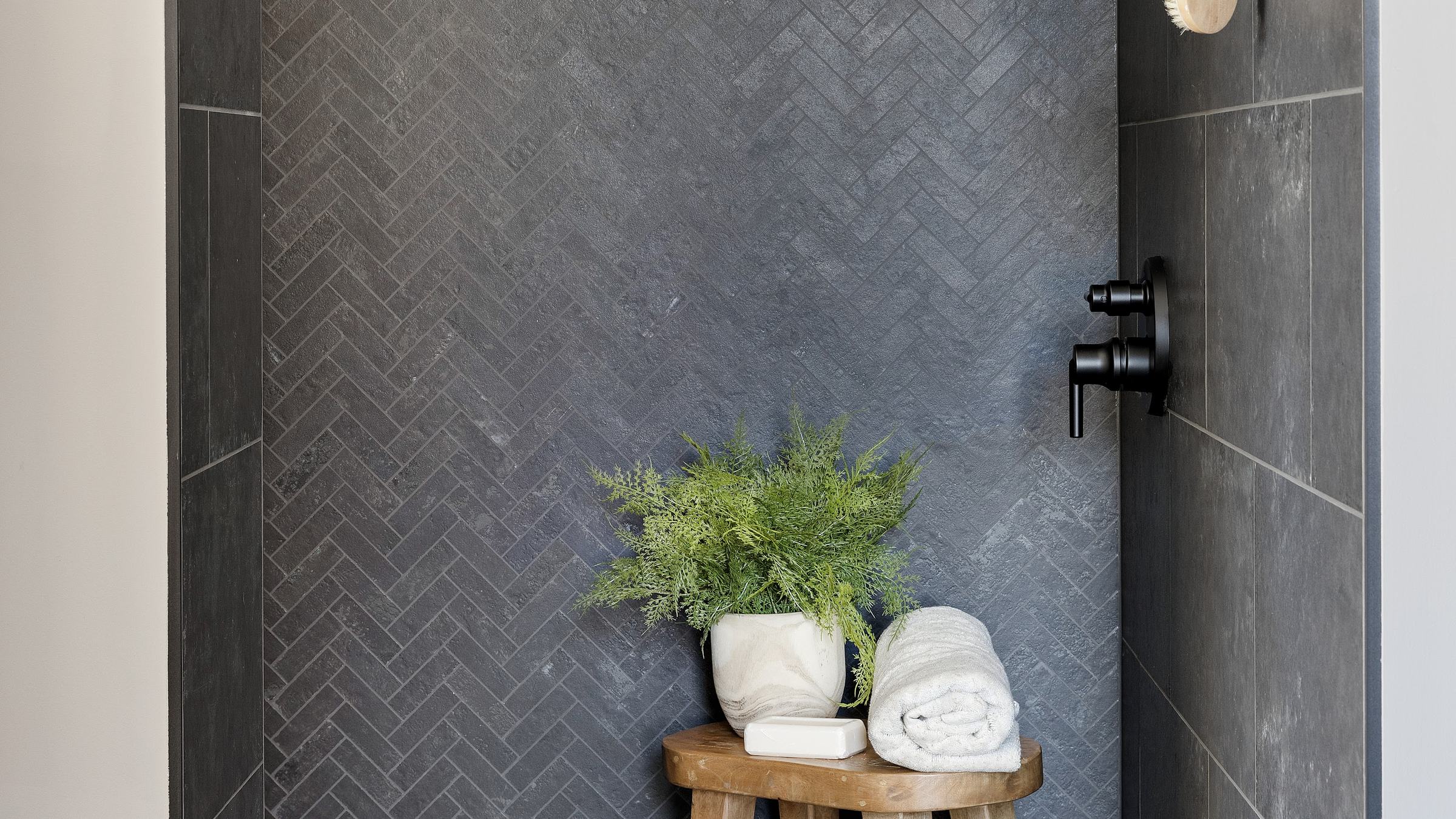 Shower with a charcoal herringbone tile wall