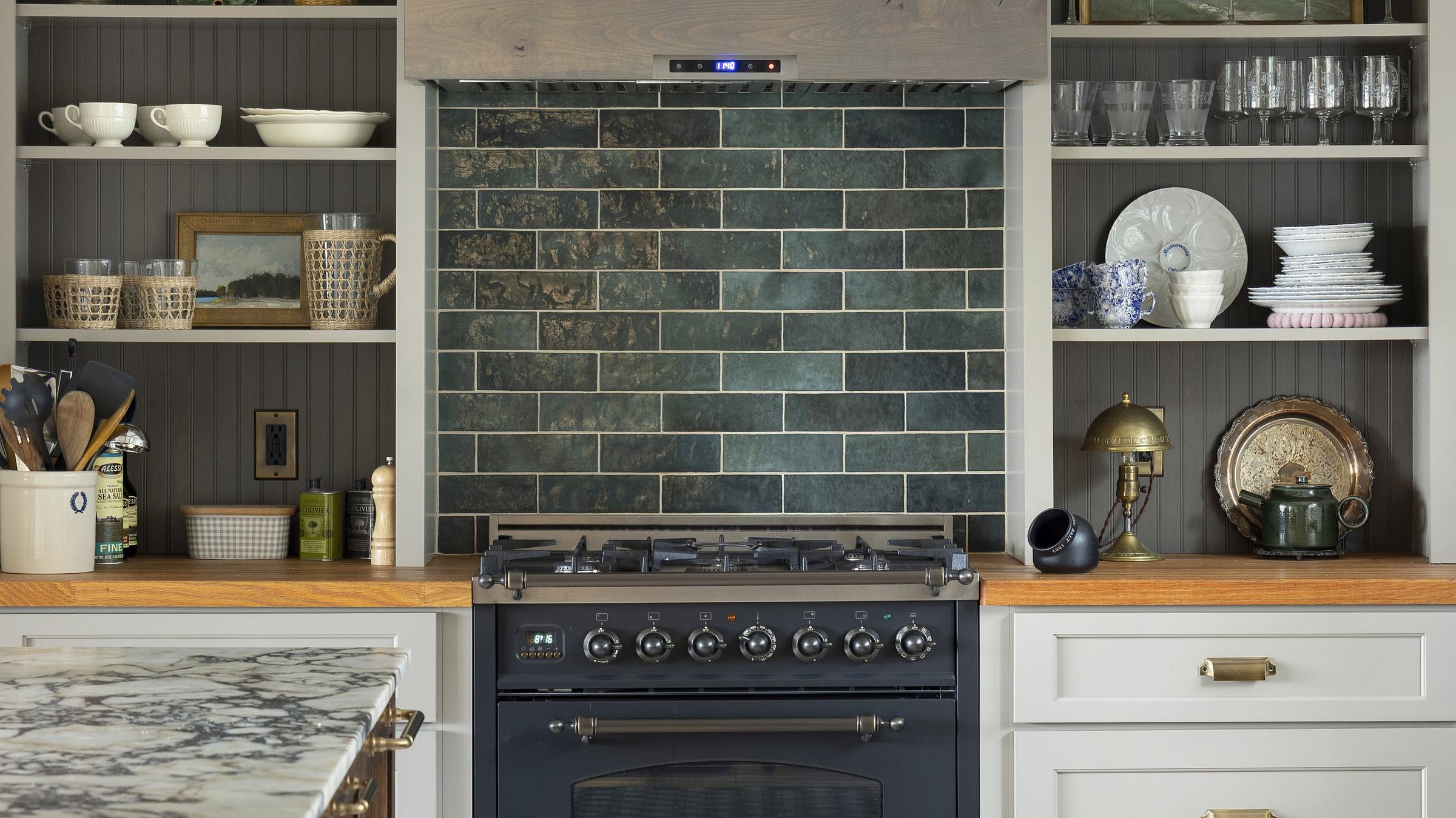 Farmhouse kitchen with a green glazed tile backsplash behind the range