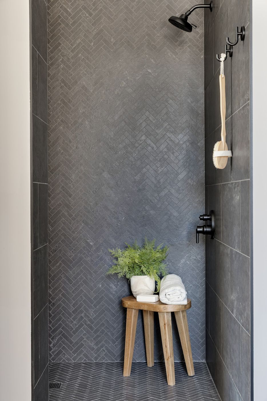 Shower with a charcoal herringbone tile wall and matching floor