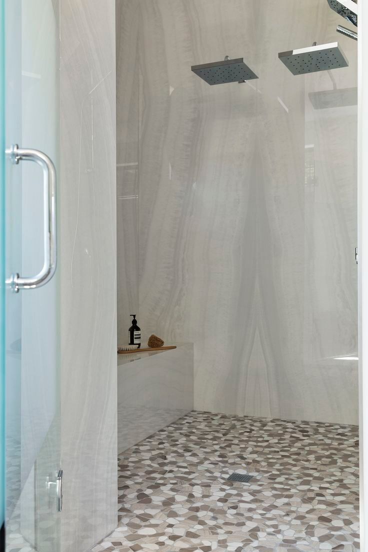 Walk-in shower with floor-to-ceiling porcelain slabs and a pebble mosaic floor