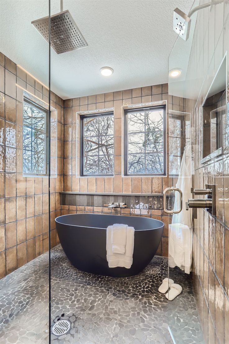 Glass-enclosed wet room with a rain shower, soaking tub and river rock floor